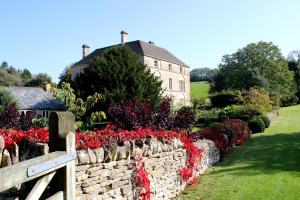 un mur en pierre avec des fleurs rouges devant une maison dans l'établissement Aylworth Manor, à Naunton