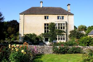 Aylworth Manor في Naunton: منزل قديم وامامه حديقة