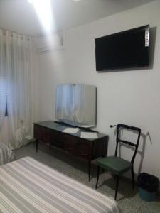 una camera da letto con TV e scrivania con sedia di B&B ca'del grillo a Castel del Rio