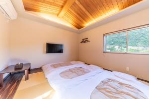 een slaapkamer met een bed en een tafel en een televisie bij 郷隅美悦 - Kyo Gu Bi Etsu in Hakone