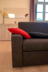 Un sofá negro con dos almohadas rojas. en La Dimora delle Zitelle Sperse - Parcheggio privato en Orvieto