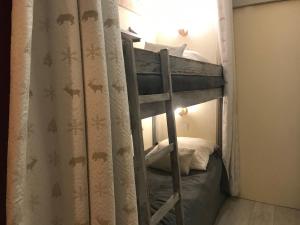 een stapelbed in een kamer met een gordijn bij au Bonheur - Praloup 1600 - Au cœur de la station et au pied des pistes - La voile des neiges - parking commun privé - local ski in Pra-Loup