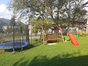 um parque infantil com um baloiço e um banco num quintal em Pokoje gościnne u Kaski em Krościenko