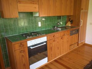 a kitchen with wooden cabinets and a stove and a sink at Chalet Garnedel in Breil/Brigels