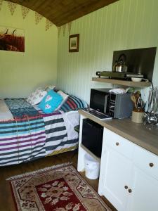 a small bedroom with a bed and a microwave at Shepherds hut Dolly wagon in Keswick +18 photos