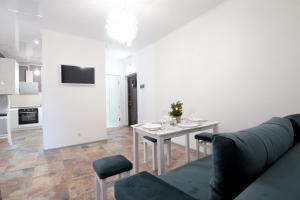 a white living room with a table and a couch at Lviv center VIP apartments new building in Lviv