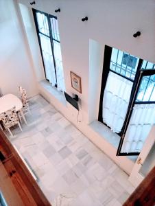 a room with four windows and a table and chairs at Apartamentos Larga 70 in El Puerto de Santa María