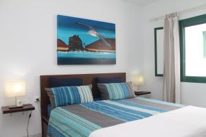 a bedroom with a bed and a bird painting on the wall at La Playa in Órzola