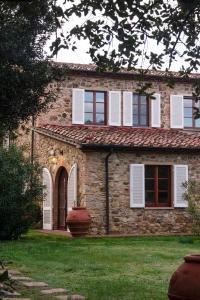 Casa de piedra con persianas blancas y patio en Poggio Cornetto en Bibbona