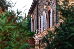 a brick building with white windows and trees in the foreground at Poggio Cornetto in Bibbona