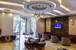 a restaurant with tables and chairs and a stone wall at Admas Grand Hotel in Entebbe