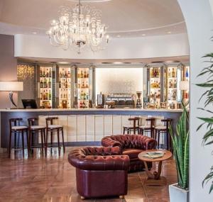 a bar with a couch and chairs in a room at Hotel Aurelia in Milano Marittima