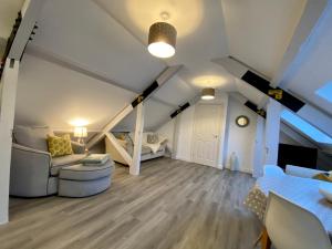 una sala de estar con muebles blancos en un ático en Nera Stay, en Leighton Buzzard