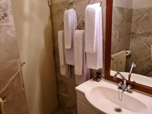 ein Badezimmer mit einem Waschbecken, einem Spiegel und Handtüchern in der Unterkunft Pension Maria in Arachova