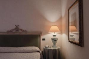 una camera con letto, lampada e specchio di Relais Ducale a Gubbio