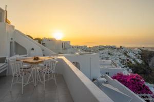 a balcony with a table and chairs and a sunset at Imer Villas in Imerovigli