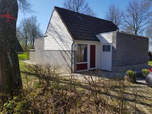 een klein wit huis met een rode deur bij Belle - Mooi Zuid Limburg in Simpelveld