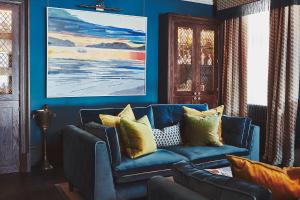 a living room with a blue couch with yellow pillows at No.26 By The Sea in Oban