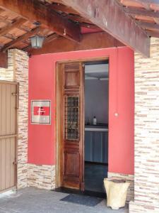 a red wall with a wooden door in a building at Hotel America in Jacareí