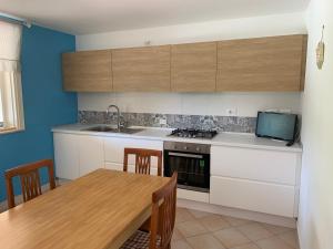 a kitchen with white cabinets and a wooden table at La Villa Rosa al Mare in Pozzallo