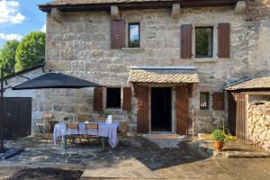 a stone house with a table and an umbrella at La Maison de Paul en Aubrac - Lozère in Fontans
