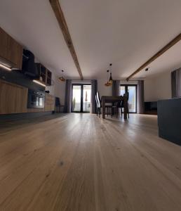 Habitación grande con suelo de madera y mesa. en Antonya Apartments en Schenna