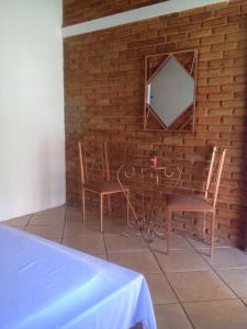a table and two chairs and a mirror on a brick wall at Vilarejo Penedo Chalés in Penedo