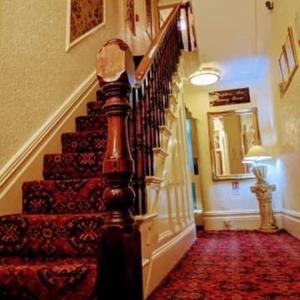 a staircase in a house with a red carpet at Gleneagles - Albert Road in Blackpool