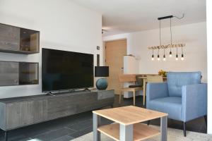 sala de estar con TV, silla azul y mesa en Panoramaresidence Hafling, en Avelengo