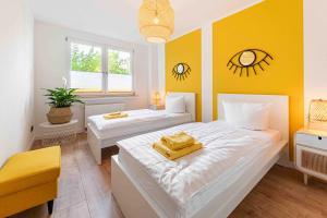 a bedroom with two beds and a yellow wall at Apartment Elbkiez - Wohnen zwischen Elbe & Altstadt, stilvoll mit Balkon! in Dresden