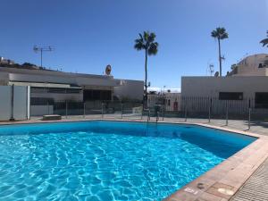 a large blue swimming pool in front of a building at Lovely apartment 2 rooms with big terrace in Puerto Rico in Puerto Rico de Gran Canaria