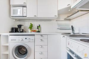 uma cozinha branca com uma máquina de lavar roupa e um lavatório em WeHost Munkkisaarenkatu em Helsinque