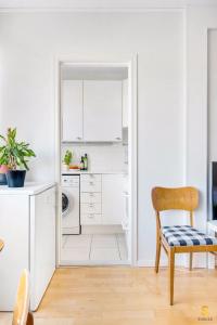 uma cozinha branca com uma cadeira e um lavatório em WeHost Munkkisaarenkatu em Helsinque