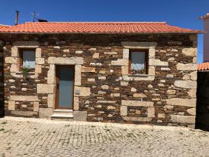 a stone house with three windows and a brick at Casa de Xisto Ti Lucília in Videmonte