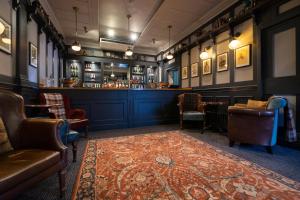 a pub with a bar with chairs and a rug at Worplesdon Place Hotel in Guildford