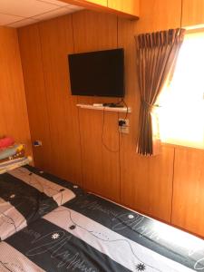 a room with a tv and a bed and a window at Komei Container Homestay in Qingshui