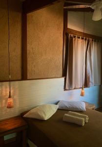 a bedroom with a bed with two pillows and a window at Condomínio Varandas da Lagoa in Praia do Rosa