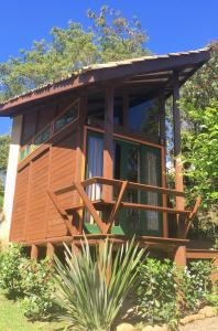 Condomínio Varandas da Lagoa في برايا دو روزا: منزل خشبي مع شرفة كبيرة على الاشجار