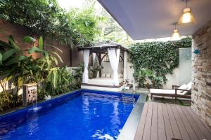 una piscina en un jardín con cenador en Frangipani Villa, en Anjuna