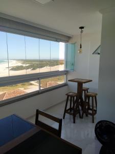 アハイアウ・ド・カボにあるapart praia grande arraial do caboのビーチの景色を望むダイニングルーム(テーブル、椅子付)