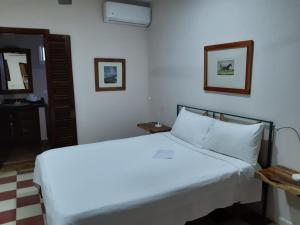 een slaapkamer met een groot wit bed met 2 foto's aan de muur bij Villa Carolina Bed and Breakfast in San Felipe de Puerto Plata