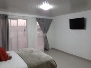 a bedroom with a bed and a television on the wall at Lesiba guesthouse in Kwamhlanga