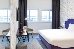 ibis Styles Amsterdam Airport في سخيبول: غرفه فندقيه بسرير وكراسي