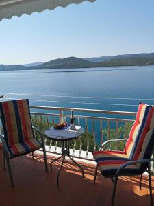 two chairs and a table on a balcony with a view of the water at Apartments Ljiljana in Klek