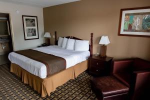 Cette chambre comprend un grand lit et une chaise. dans l'établissement Regency Inn, à Monroeville