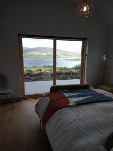 a bedroom with a bed and a large window at Treaslane Stable Rooms in Skeabost