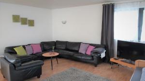 a living room with a black leather couch and a table at Apartment zum Wohlfühlen in ruhiger Lage in Pfungstadt