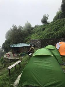 a person sitting on a bench next to a tent at SERENITY CAMPS, MUSSOURIE in Mussoorie
