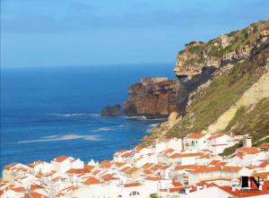 un groupe de maisons blanches sur une colline à côté de l'océan dans l'établissement Casa da Candida one place, many things, à Nazaré