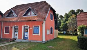 een rood huis met blauwe deuren en een tuin bij Terme Catez Apartment 7 in Čatež ob Savi